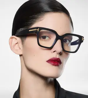 A woman wearing a black and gold pair of glasses with red lipstick and a black top