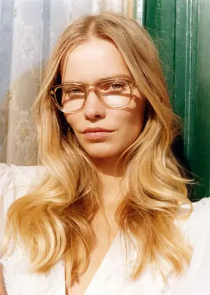 A woman with blonde hair wearing glasses and a white dress