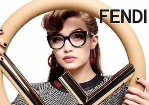 An advertisement featuring a woman holding a pair of eyeglasses with a gold frame and the word Fendi written above her