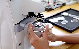 Optician holding an eyeglass lens while using a lens measurement device