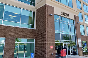 Exterior of a modern brick and glass office building marked 1020 with accessible entrances