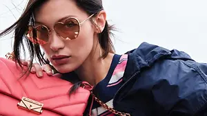 Woman wearing heart-shaped sunglasses beside a pink handbag