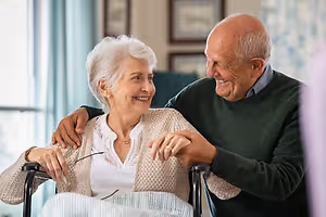 Elderly couple sharing a happy moment in a room with white walls and picture frames
