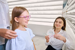 A young girl tries on glasses in an optometrist's office.