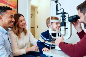 A child is getting an eye exam with a family member in an eye doctor's office