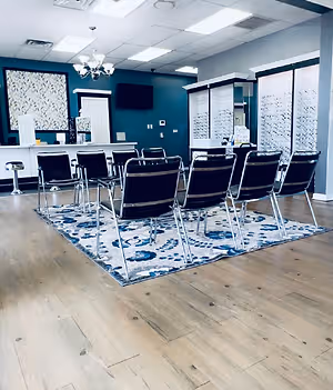 A large room with a blue wall, a chandelier, a rug, and several chairs and tables in it.