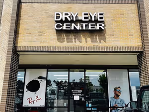 The front of the Dry Eye Center building with a man wearing sunglasses on the window glass.