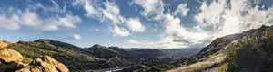 A mountain view with a road and a sky with clouds.