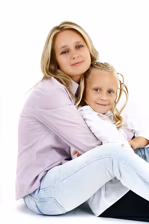 A woman and a little girl are sitting close to each other and smiling for a photo.