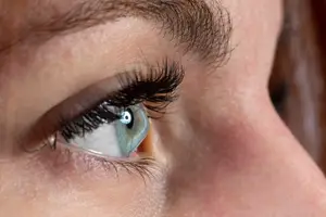 Close up of a woman's eye with eyelashes and a light reflection on her cornea