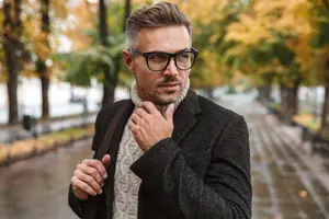 A man adjusting his collar in a park