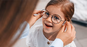 doctor fitting eyeglasses to a young girl