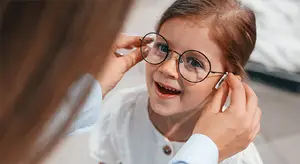 doctor fitting eyeglasses to a young girl