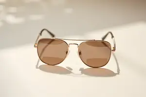 Golden aviator sunglasses with brown lenses on a white background