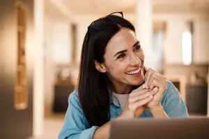 A smiling woman sitting at a desk with a laptop in front of her