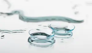 Two contact lenses with water droplets on a white surface