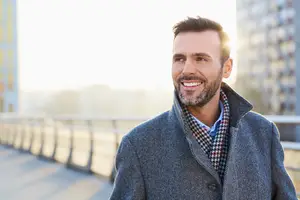 A man standing and smiling in front of a building