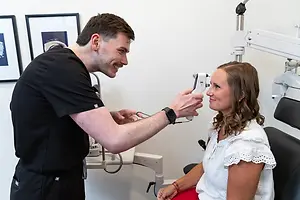 A man doctor is checking the eyes of a female patient in a clinic