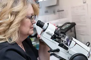 A woman in a lab looking through a microscope