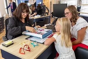 Three women are looking at a box of glasses in an office