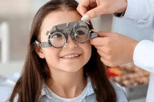 A girl having her eye examined with a phoropter by a doctor
