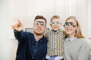 A family is wearing optical glasses and posing for a photo in a room