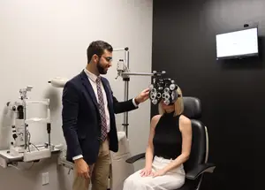 Eye doctor performing eye exam to a young blonde woman