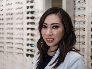 Dr. Elizabeth Tran in front of a wall of eyeglasses