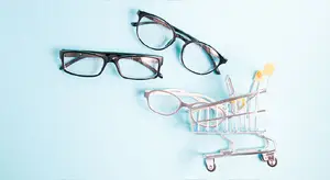 Three pairs of eyeglasses and a shopping cart on a blue background