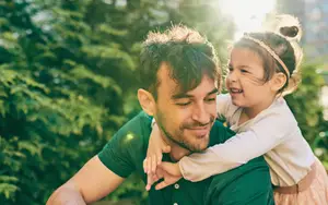 A young girl is sitting on the shoulders of a man who is smiling at her