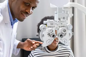 A man is giving a young girl an eye test with a machine