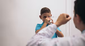 A doctor is examining a young boy's eye using a medical tool.