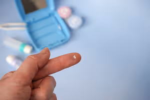 A hand pointing to a contact lens on a blue background