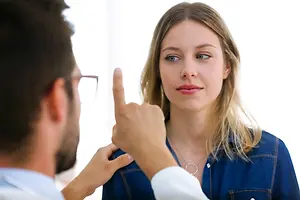 A doctor is examining a patient in a clinic with a white background.