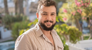 Smiling bearded man outdoors in a beige shirt