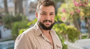 Smiling bearded man outdoors in a beige shirt