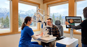 A medical team using advanced diagnostic equipment in an examination room with a scenic mountain view through the windows