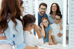 A family is in a room with mirrors and they are looking at the frames in the mirror