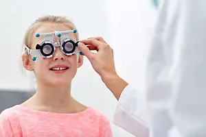 A young girl is getting an eye exam from an optometrist at the clinic.