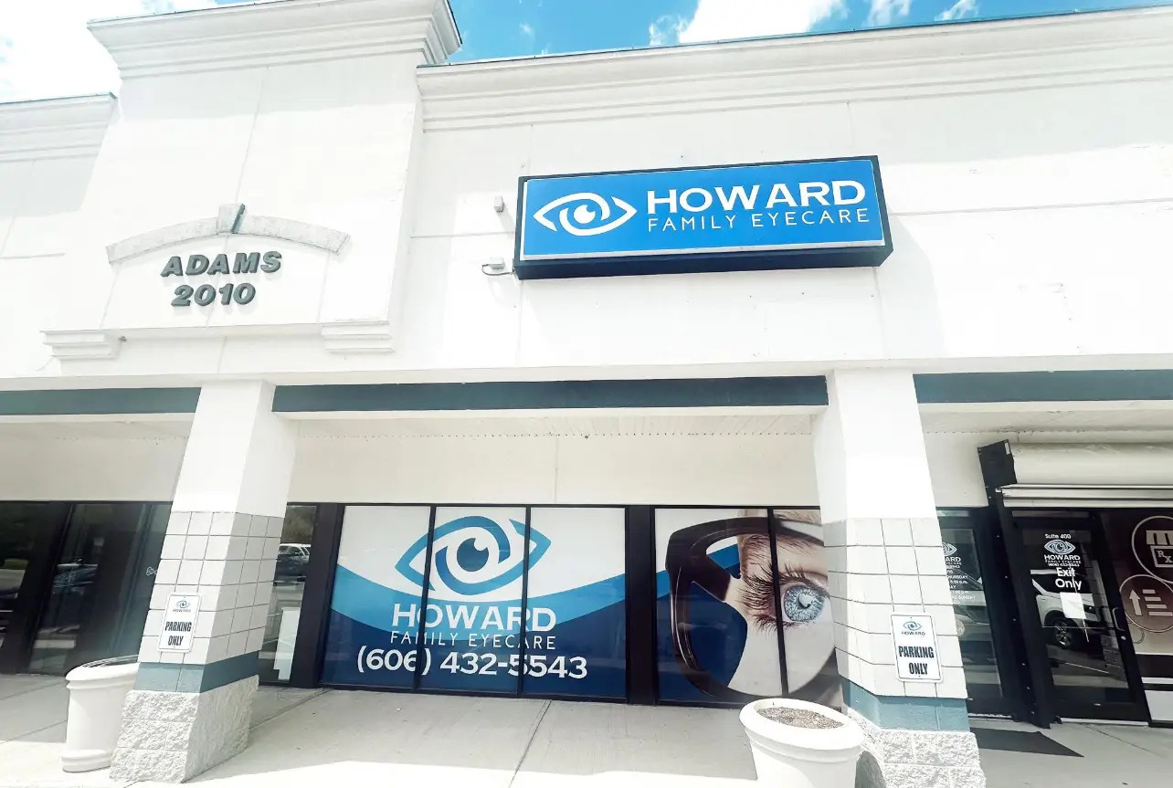 A commercial building for Howard Family Eyecare with a blue sign, glass windows, and a glass door
