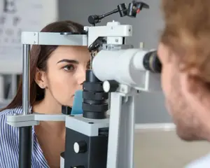 A woman is having her eyes examined by a man in a clinic.