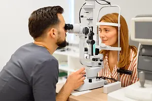 Optometrist examining a woman's eyes with a slit lamp