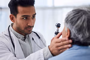 A doctor is examining a patient's ear with a medical instrument