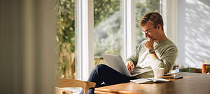 A man sitting on a chair in a room and using a laptop