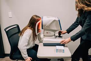 An optometrist uses an autorefractor on a patient at an eye clinic.