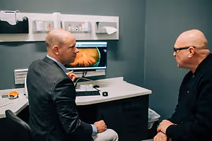 Two men in a medical office talking about an image on a computer monitor