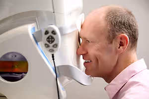 A man is looking into a device with a light on the screen