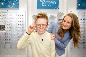 A woman and a boy standing in front of a display of glasses at a store