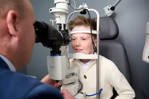A young boy has his eyes examined by a doctor using a machine in a clinic.