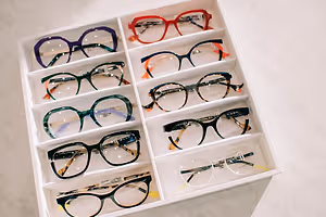 A white display box containing multiple pairs of glasses in different colors and styles.